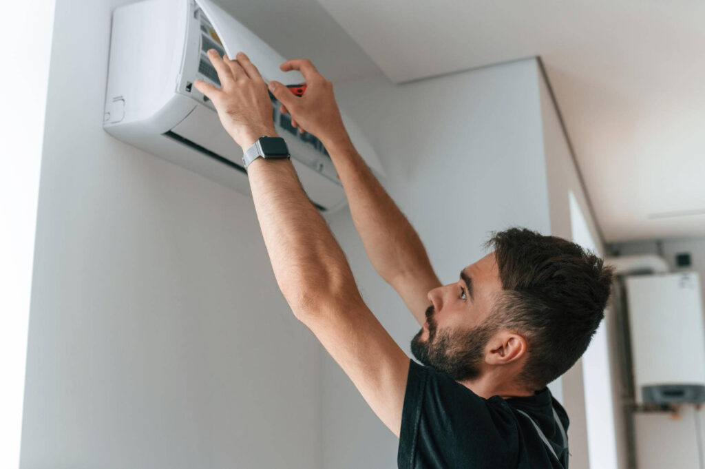 Technician servicing indoor air conditioner unit at home